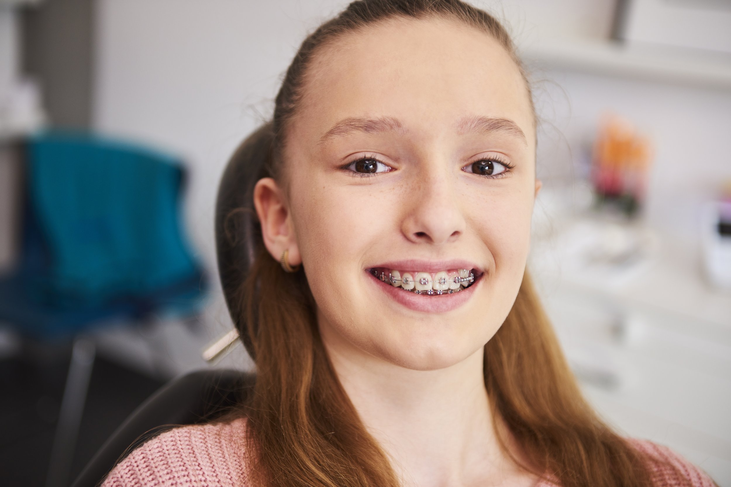 Young girl with braces smiling at the camera.