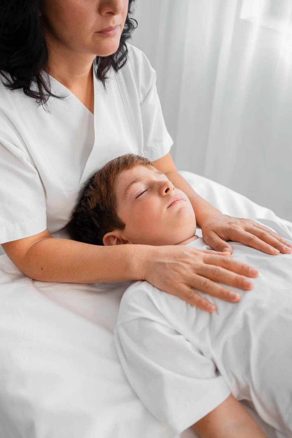 A dentist checking the a young boy on a dental chair.