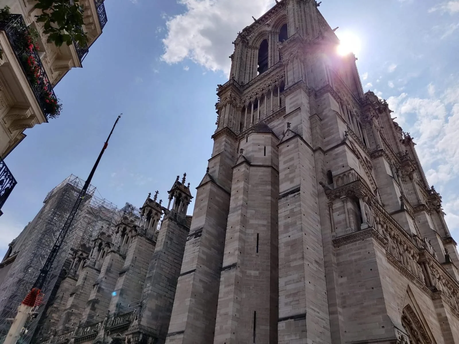The Notre-Dame Cathedral in Paris France, viewed from below with a clear sky and the sun shining behind the tower.