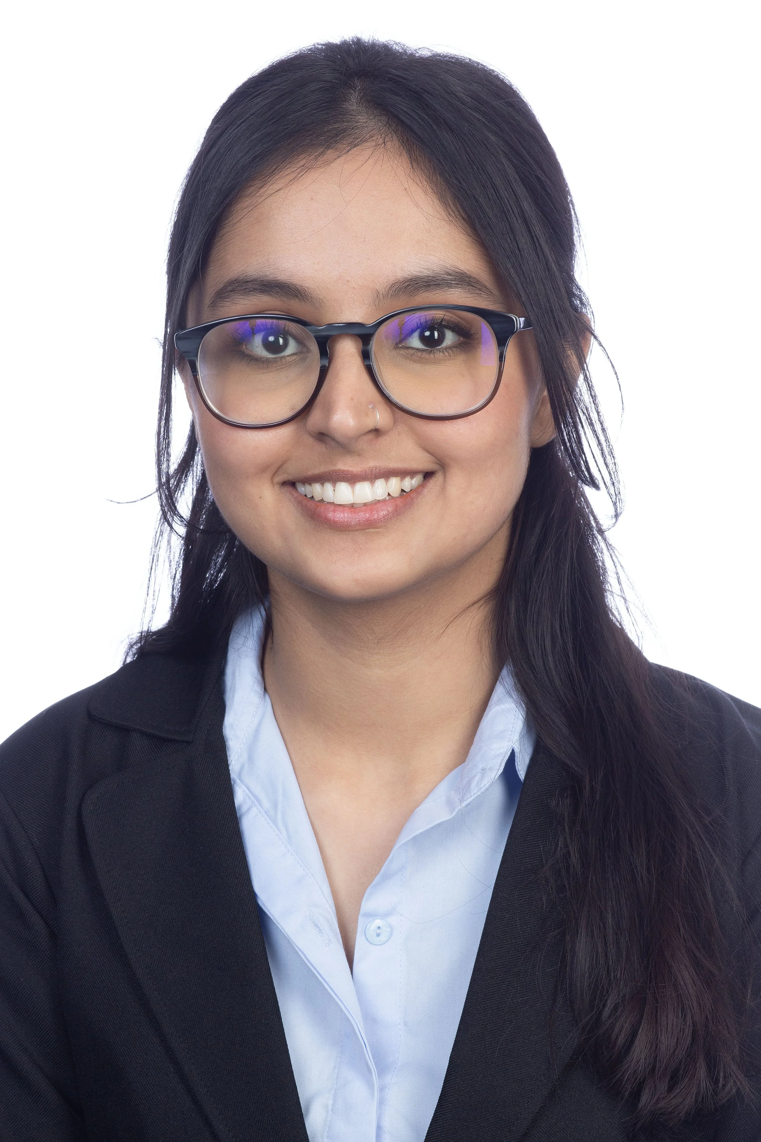 Young woman with long dark hair wearing glasses, a black blazer, and a light blue collared shirt, smiling against a white background.