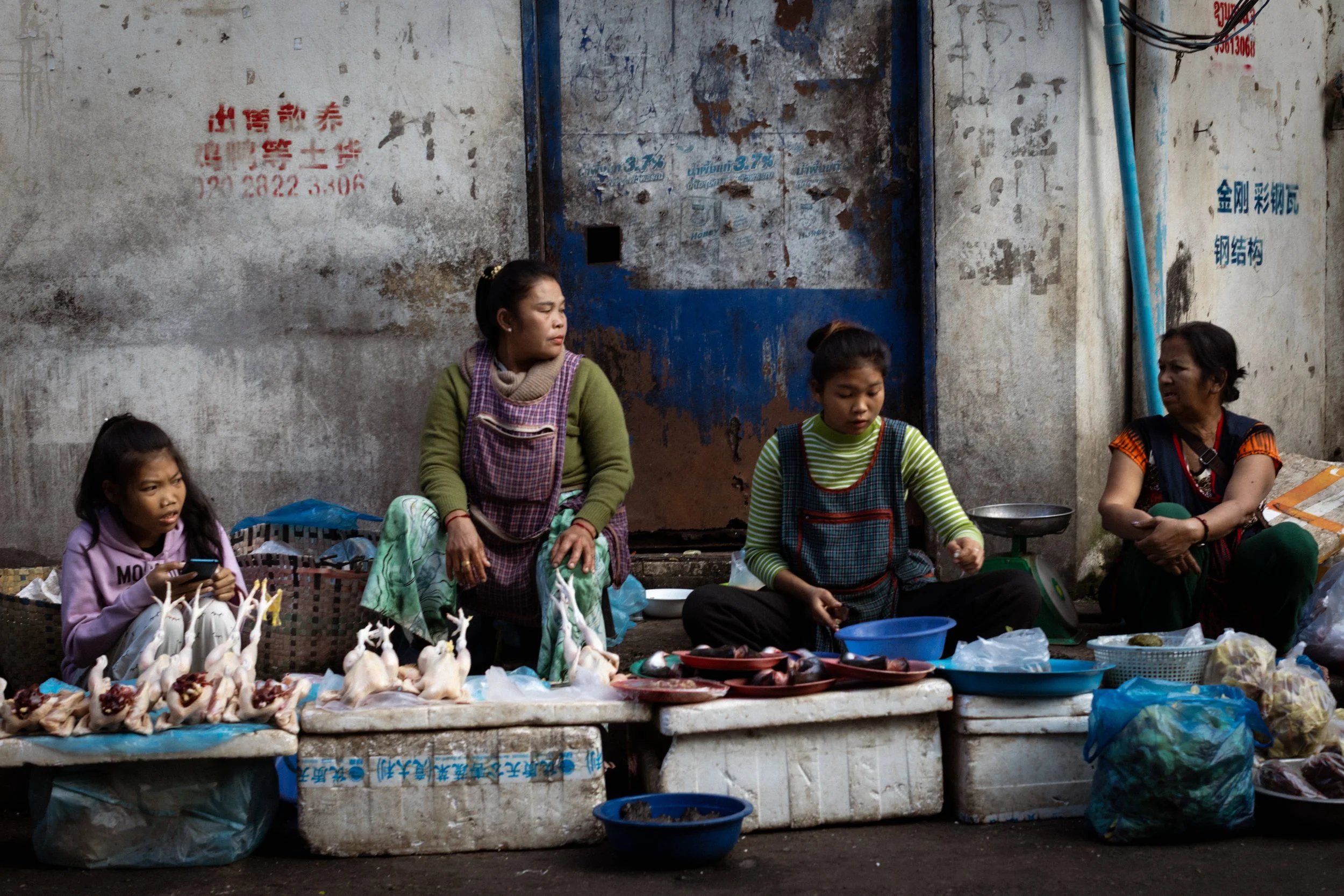 Traders selling fish gossip between themselves at the Thong Khan Kham morning market. Vientiane, Laos, 2023