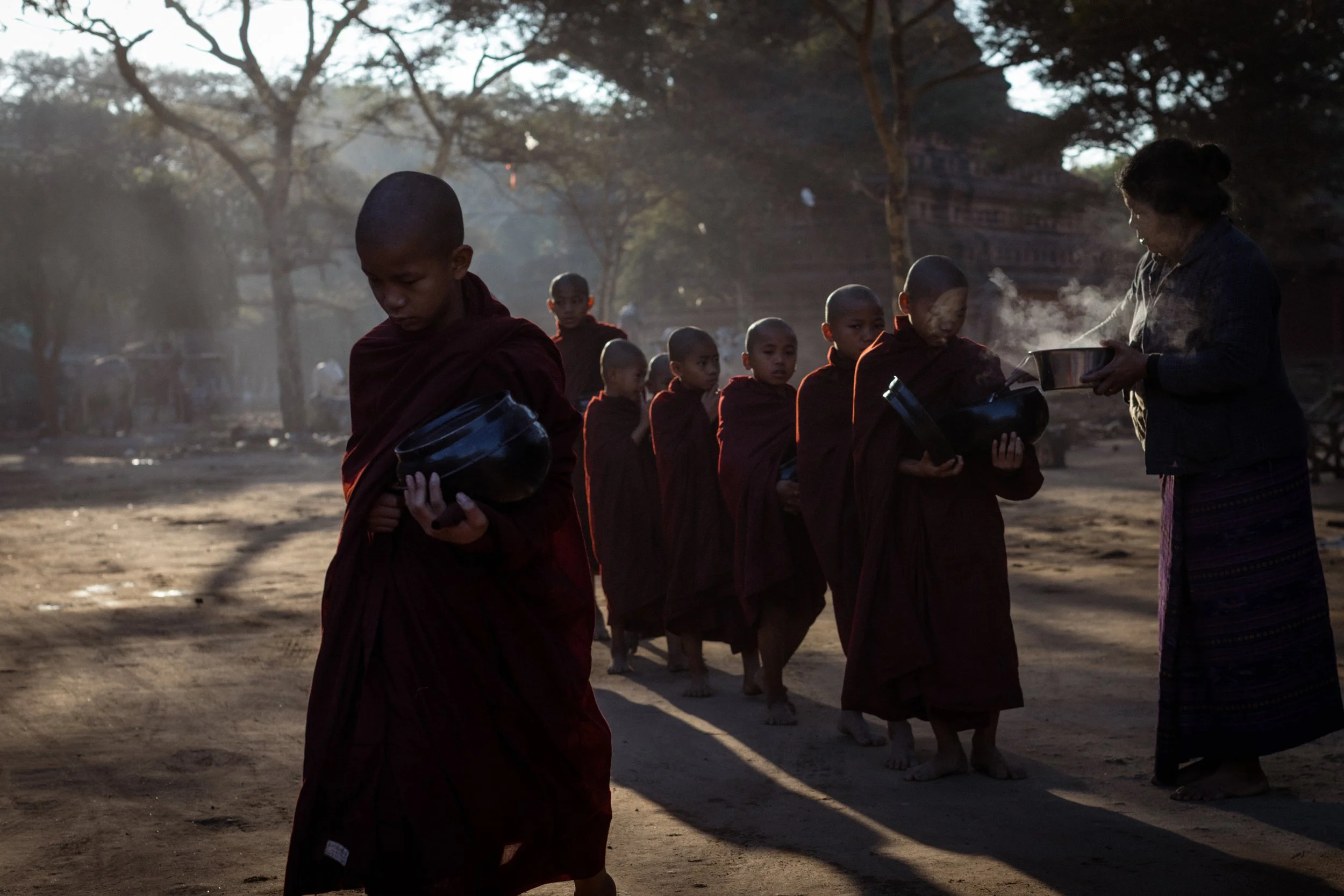 Novice Buddhist Monks collect rice early in the morning. Many of the monks are orphans; they spend most of their lives in the monastery, where they are supported with food and education. Bagan, Myanmar, 2020