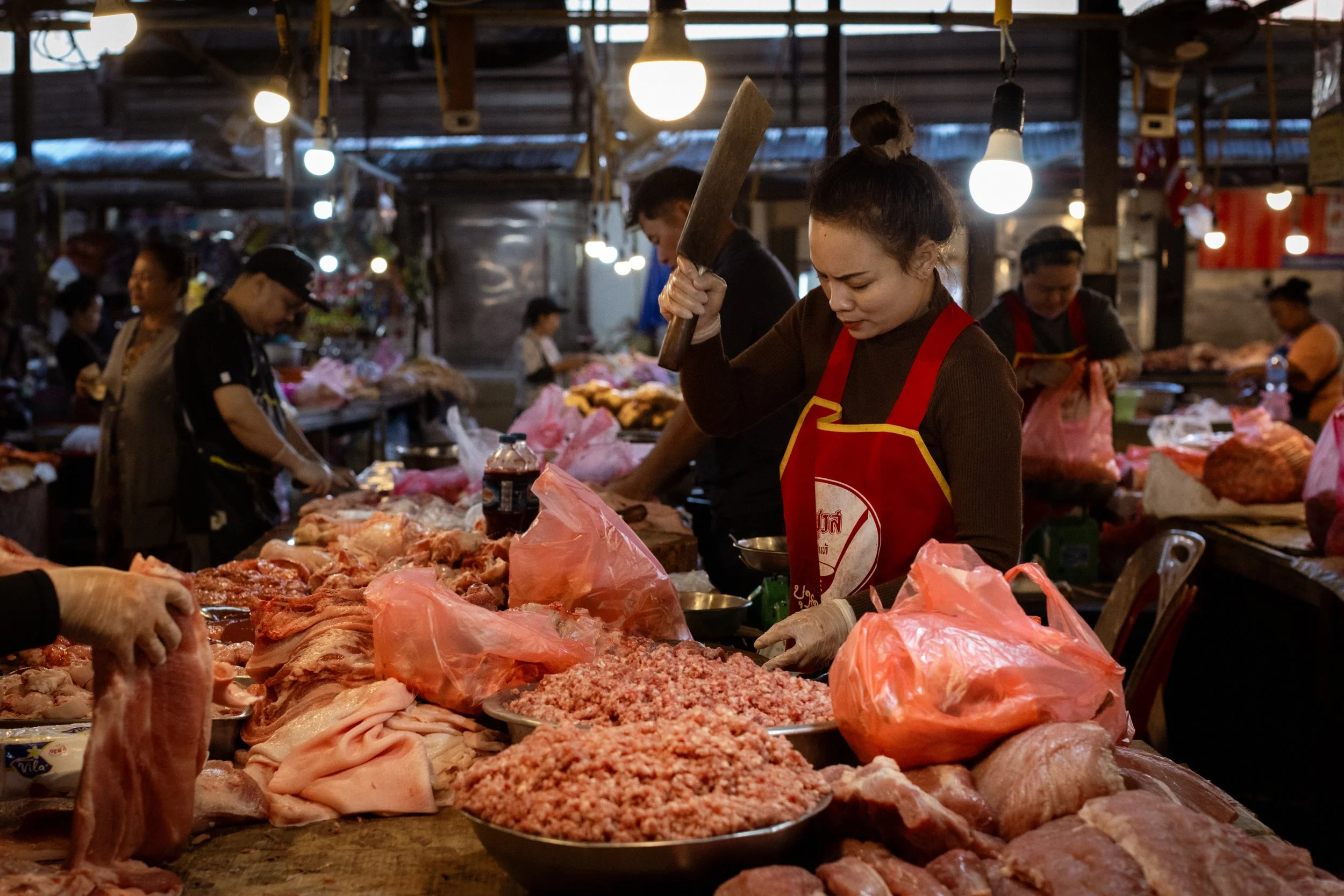 A trader butchers meat at the Thong Khan Kham morning market. Vientiane, Laos, 2023