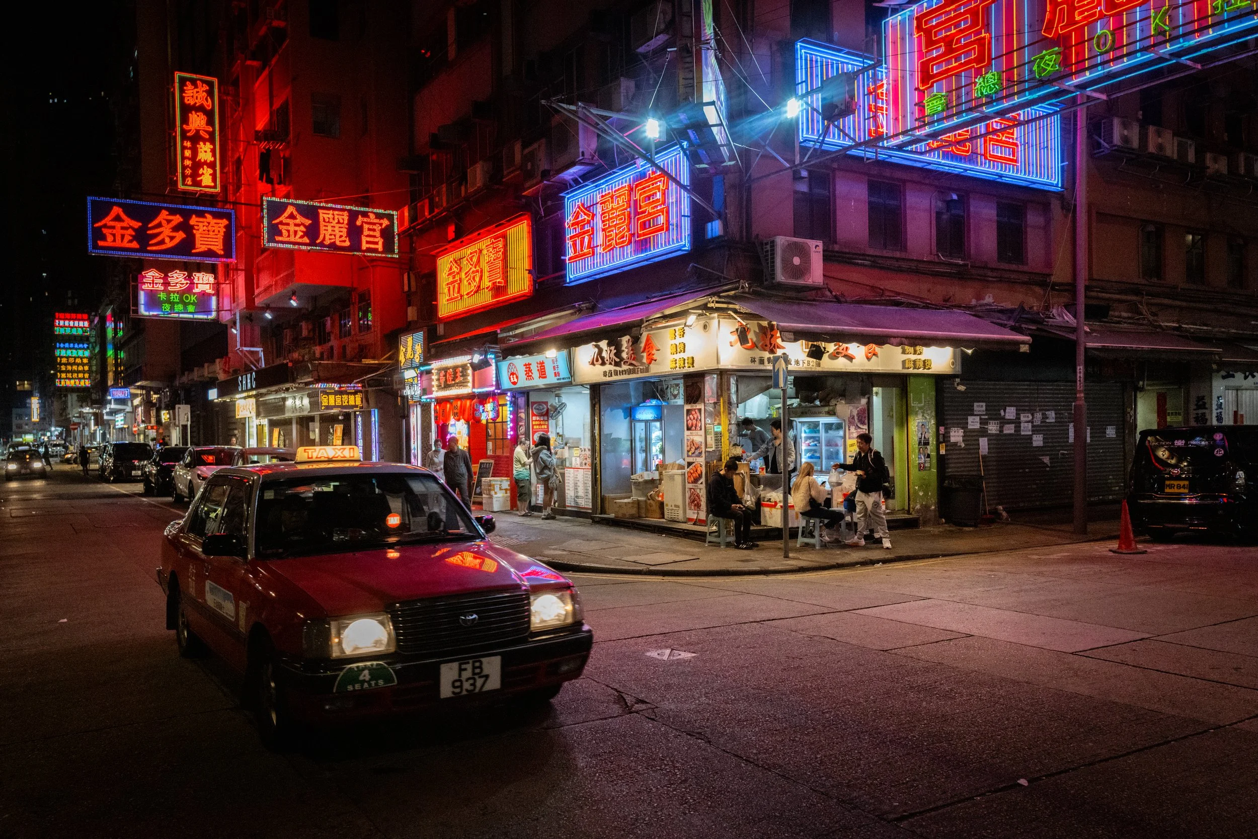 A red taxi travels past the infamous neon signs of downtown Kowloon. Hong Kong, China, 2025