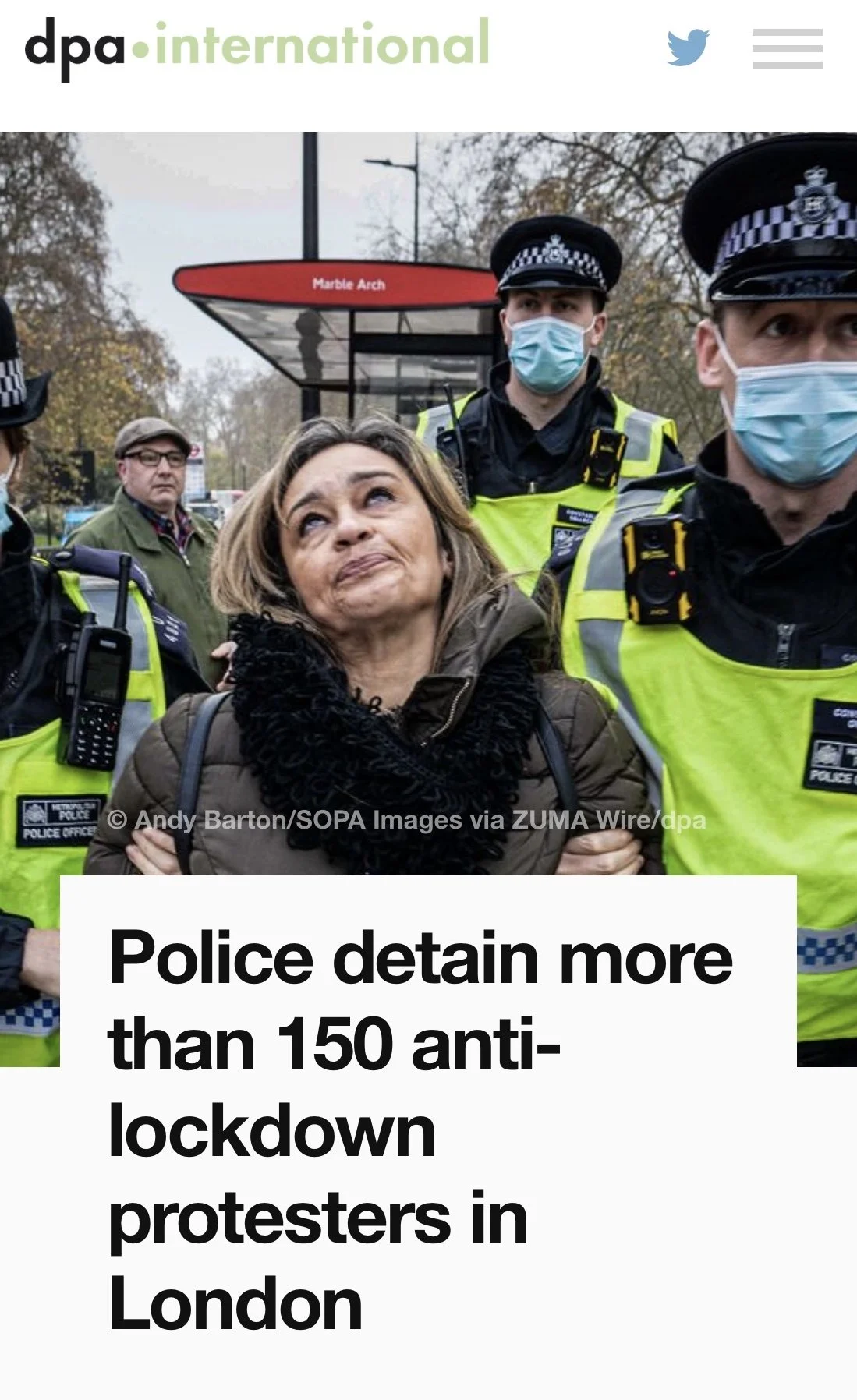 A woman being detained by police officers, some wearing masks, at a protest in London.