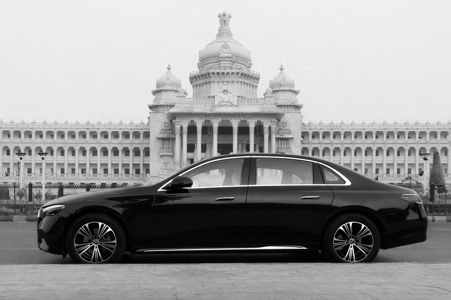 Black mercedes e class sedan parked in front of a historic building, the Vidhana Soudha in Bangalore, black and white photograph.