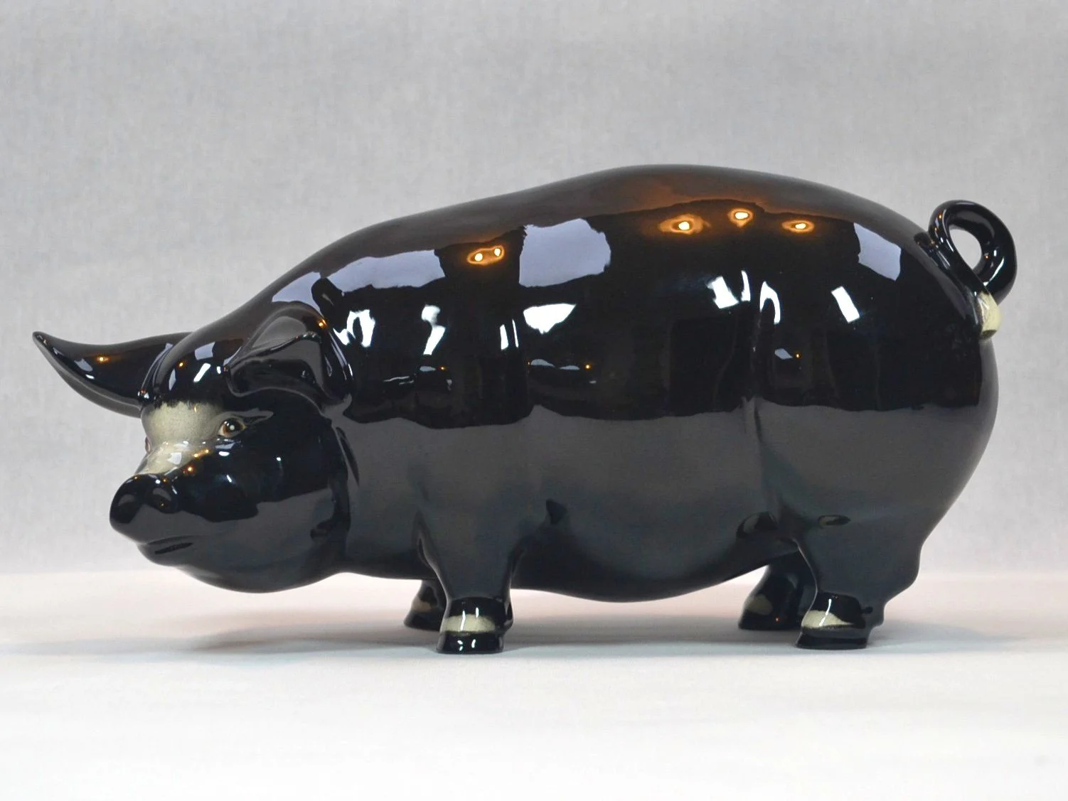 A black ceramic figurine of a pig with a glossy finish.