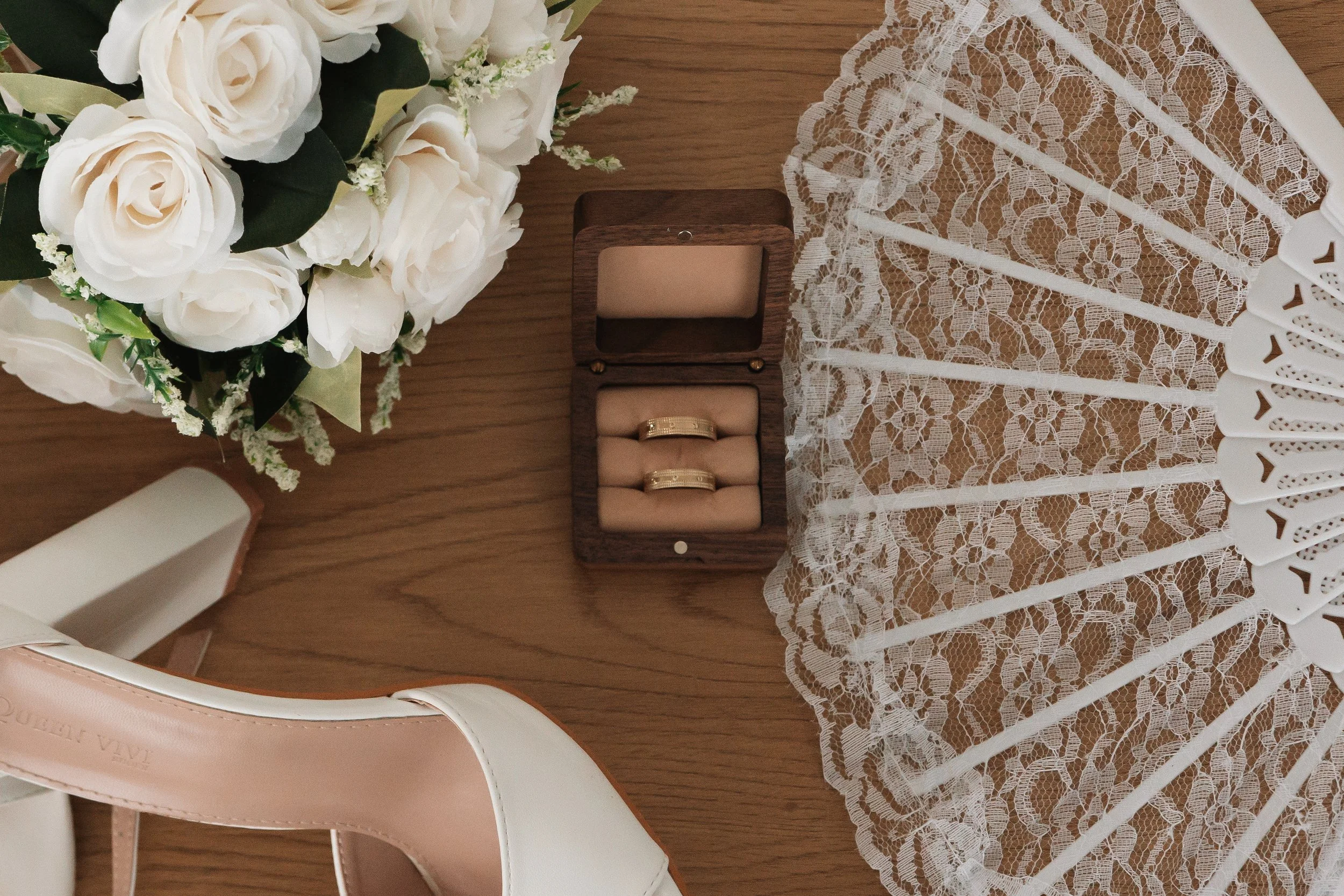 Verlobungsringe in einer Holzkiste, weiße Hochzeitsstrauß, Spitze-Tischdecke, weiße Hochzeitsschuhe, Holz Tisch