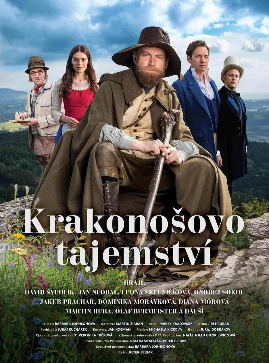 A group of five people in historical clothing, with a scenic landscape and cloudy sky in the background. The person in the center is sitting with a staff, dressed as a traveler or explorer, while the others stand behind, dressed in period costumes from different eras.