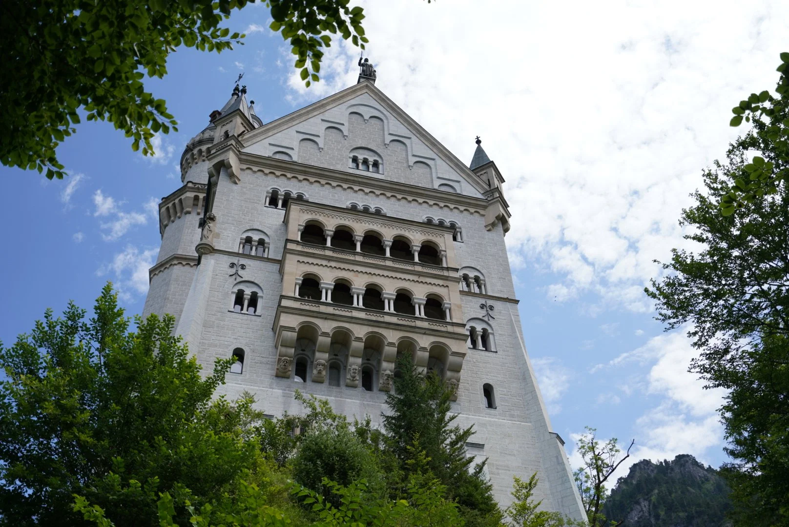 Vista del castillo de Neuschwanstein con cielo azul y árboles verdes