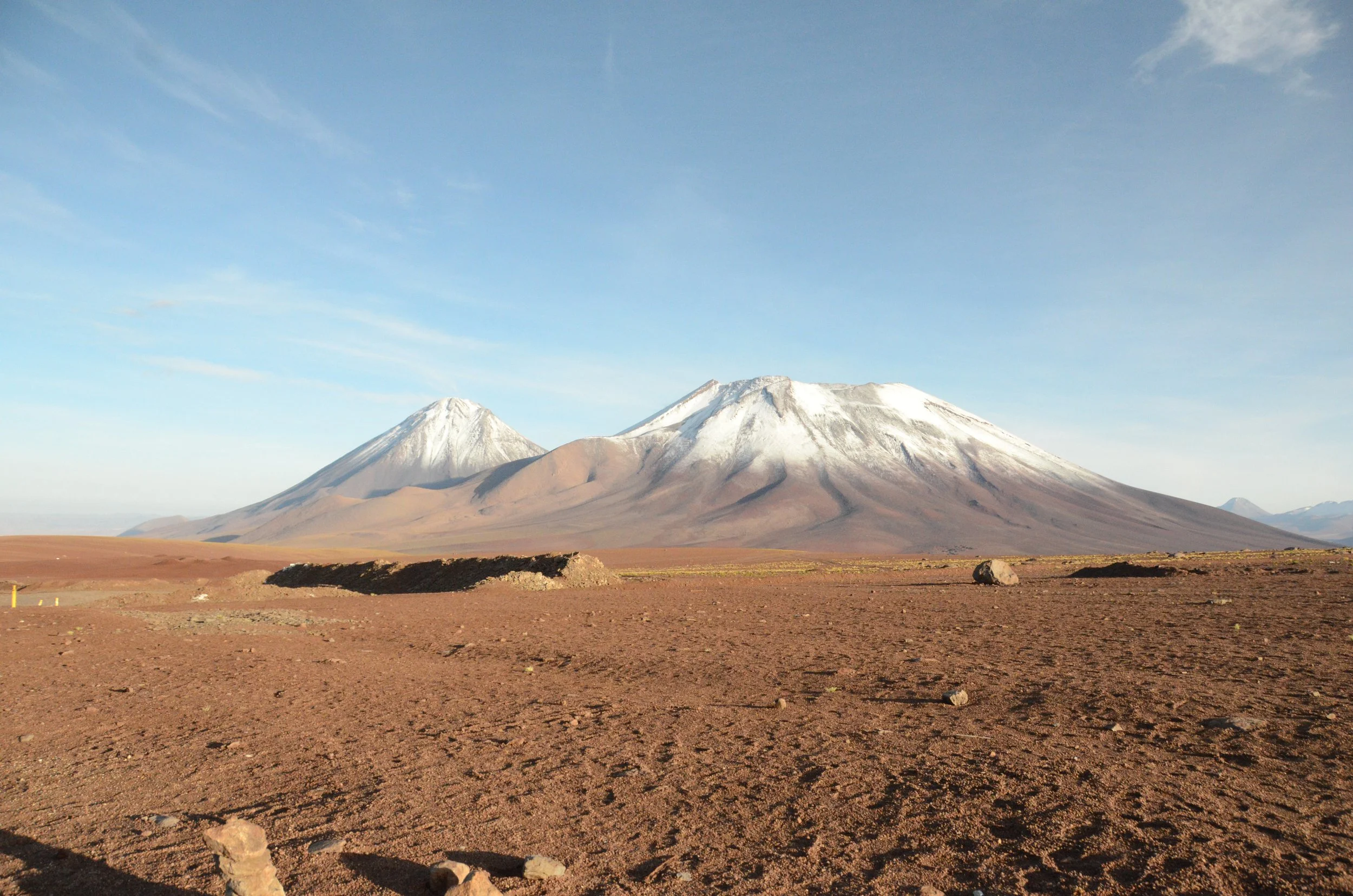 Vista de un desierto con montañas volcánicas con picos cubiertos de nieve bajo un cielo despejado.