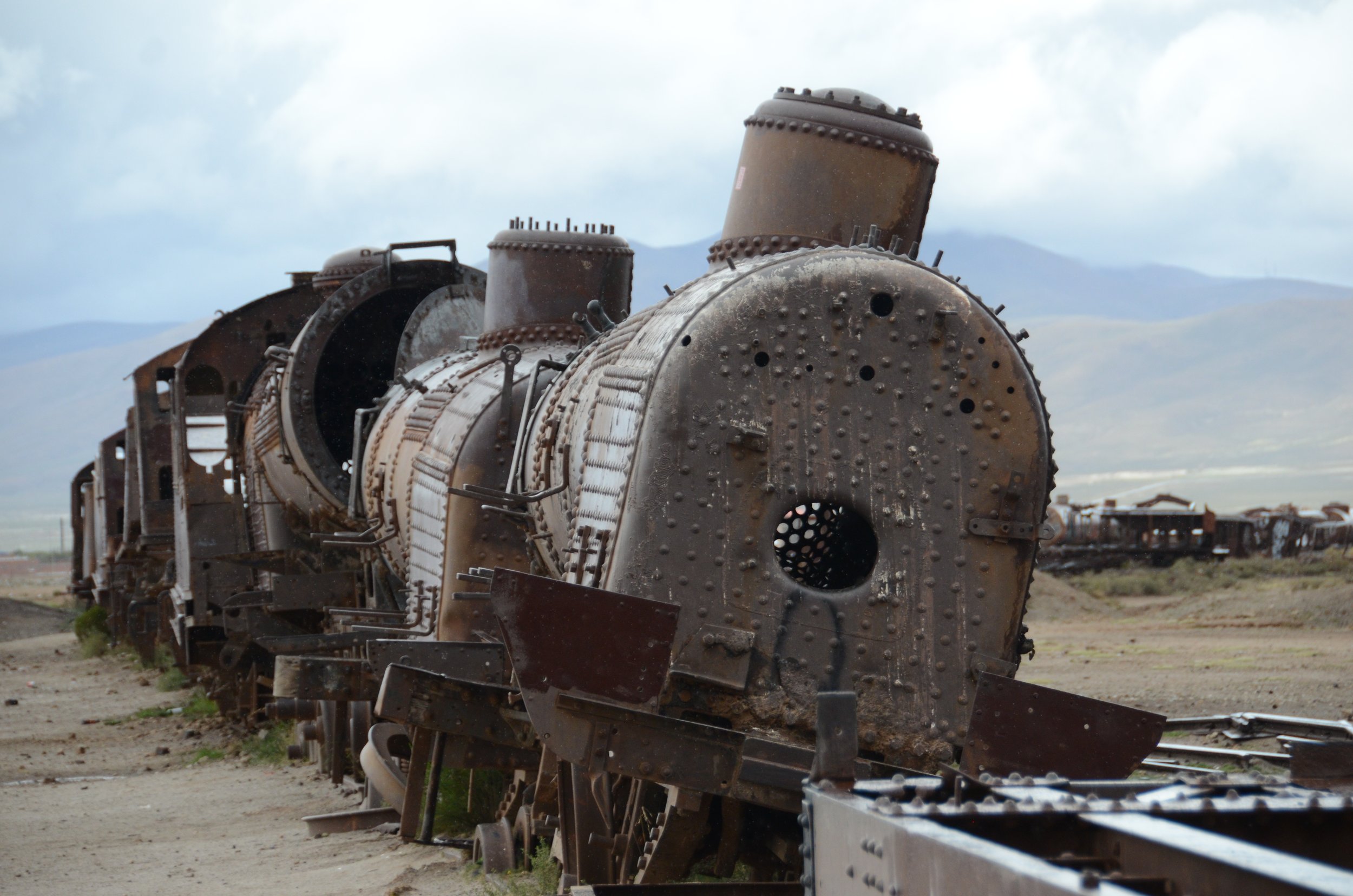 Locomotora antigua y oxidada en medio del desierto, en un estado de abandono y deterioro.