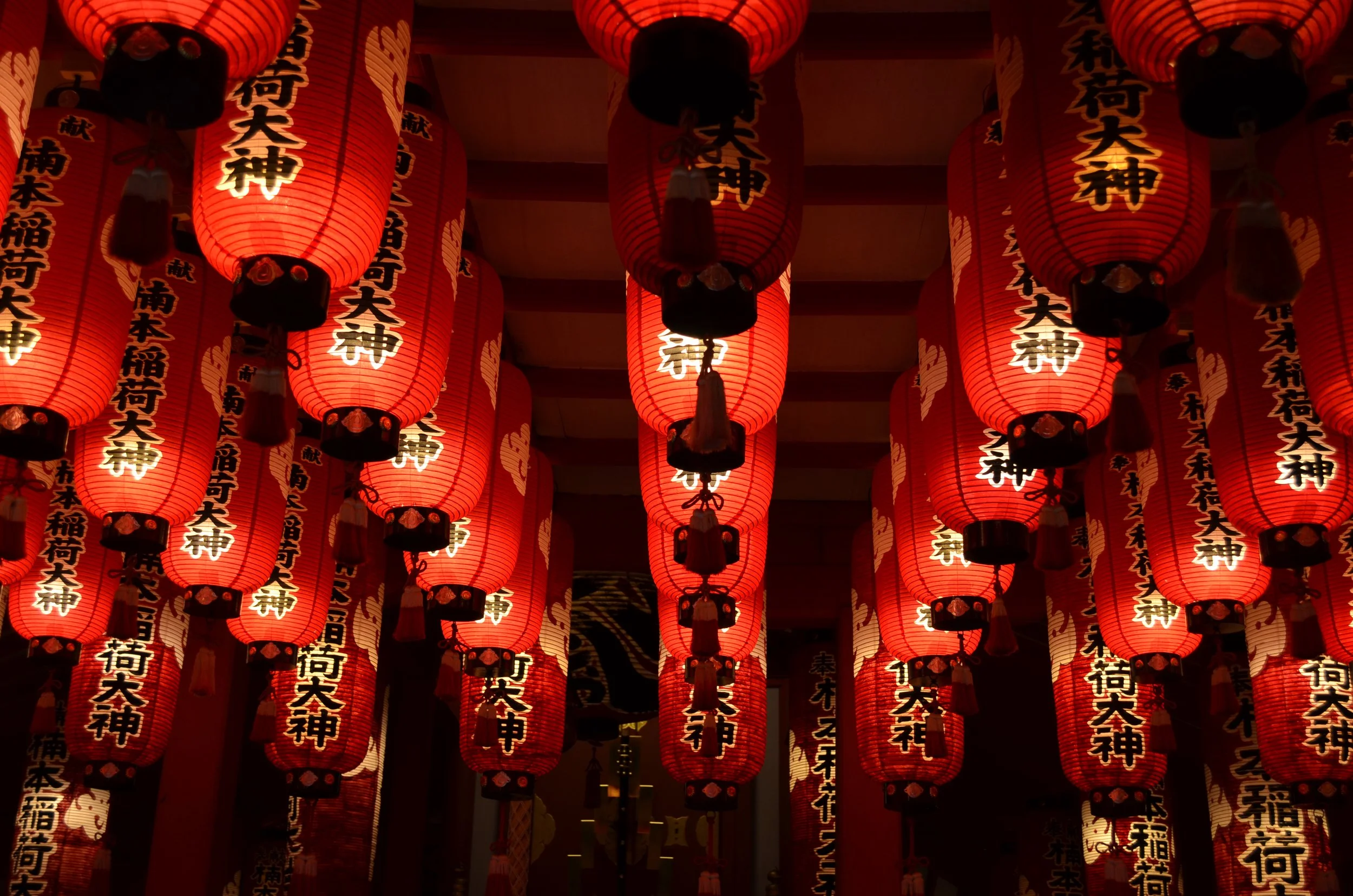 Farolillos rojos de papel con caracteres en japonés, colgados en un entorno de festividad o celebración tradicional japonesa.