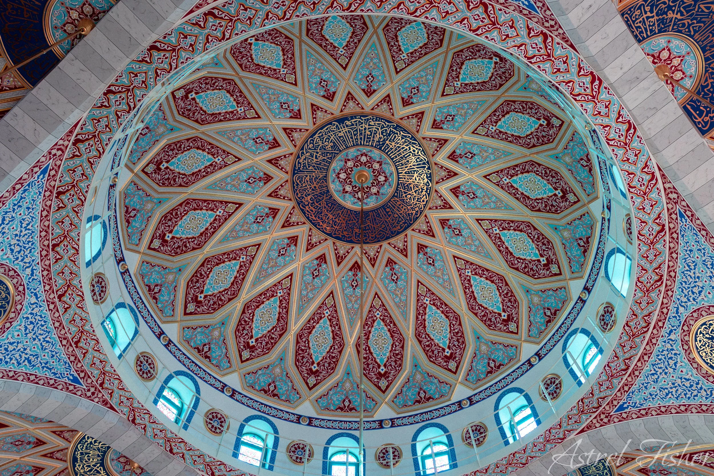 Intricate ceiling with colorful geometric and floral patterns, arched windows, and blue accents.