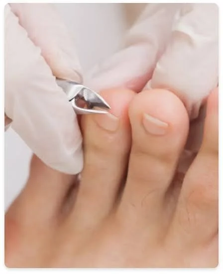 A person receiving a pedicure, with a nail technician using a cuticle pusher on their toenail.