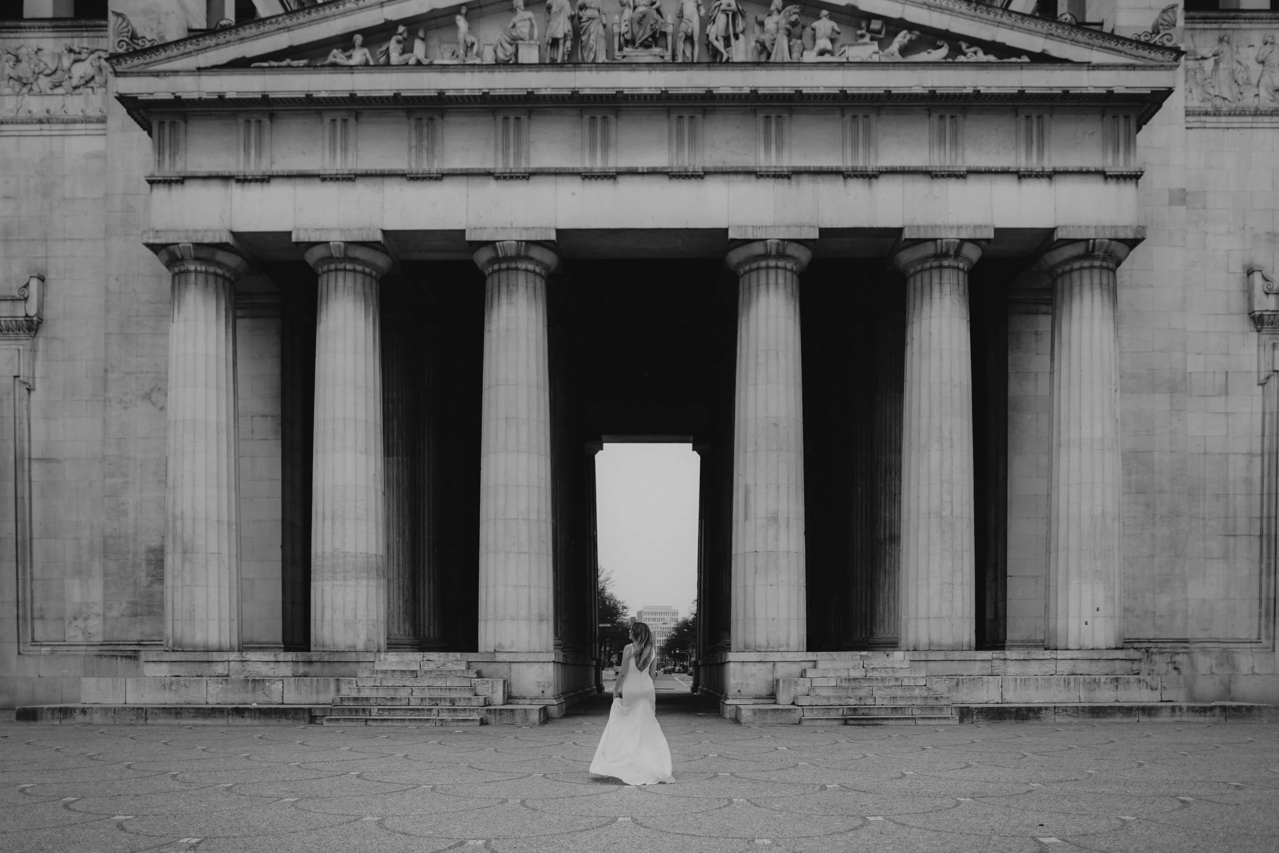 Frau in weißem Brautkleid vor dem Brandenburger Tor in Berlin, schwarz-weiß aufgenommen.