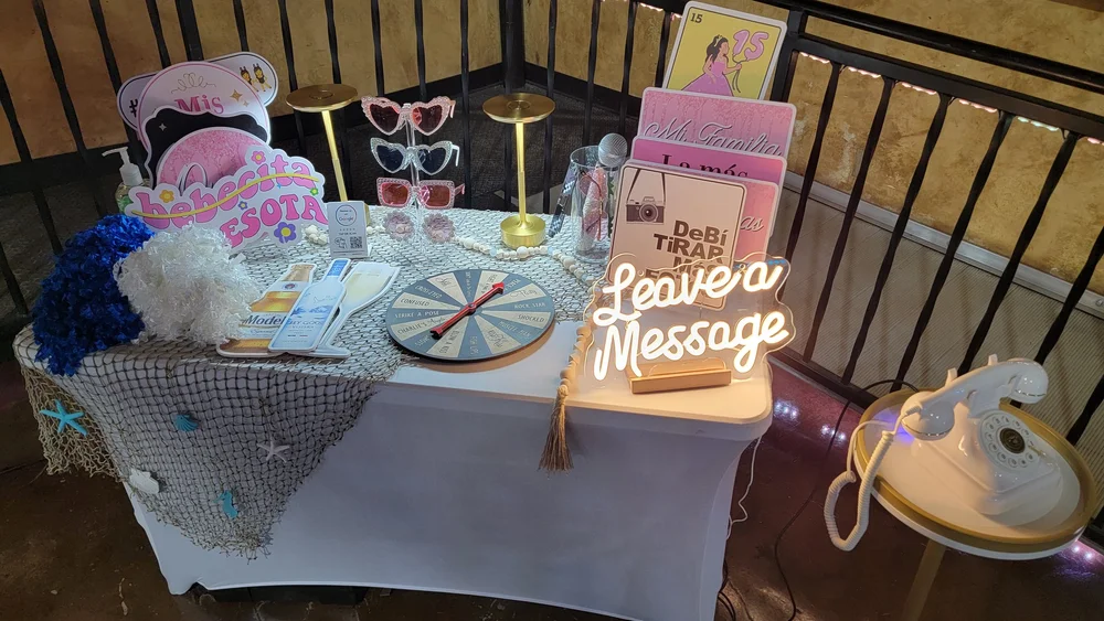 The styled prop table at a quinceañera, with photo props and the audio guestbook set up on it