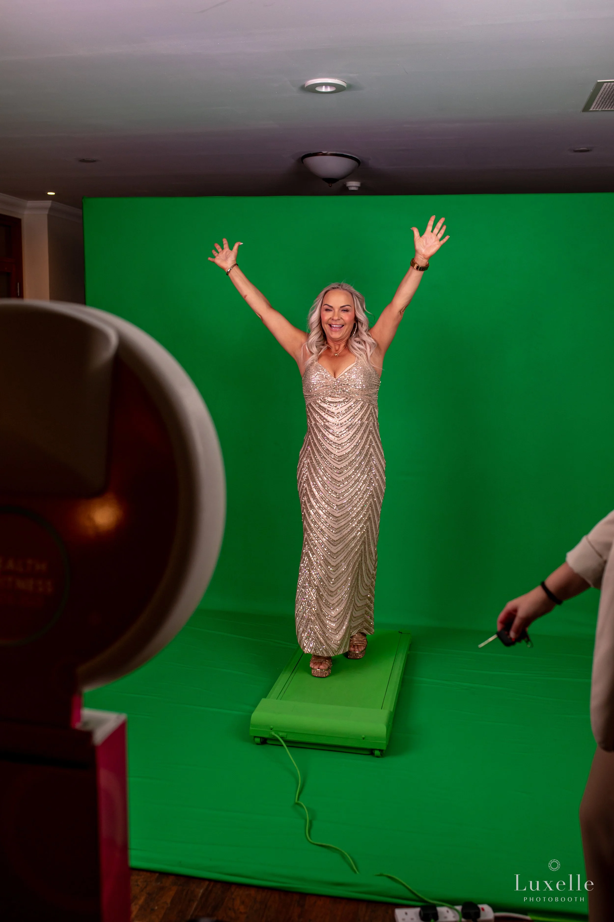 Guest in a sparkly gold dress posing at a Luxelle interactive green screen photo booth activation at an upscale event in Southern California