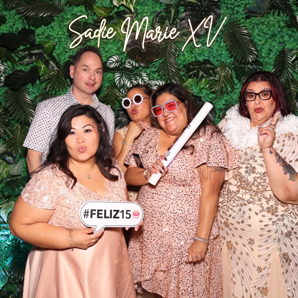 A group of guests in a studio-lit Luxelle booth portrait at a quinceañera