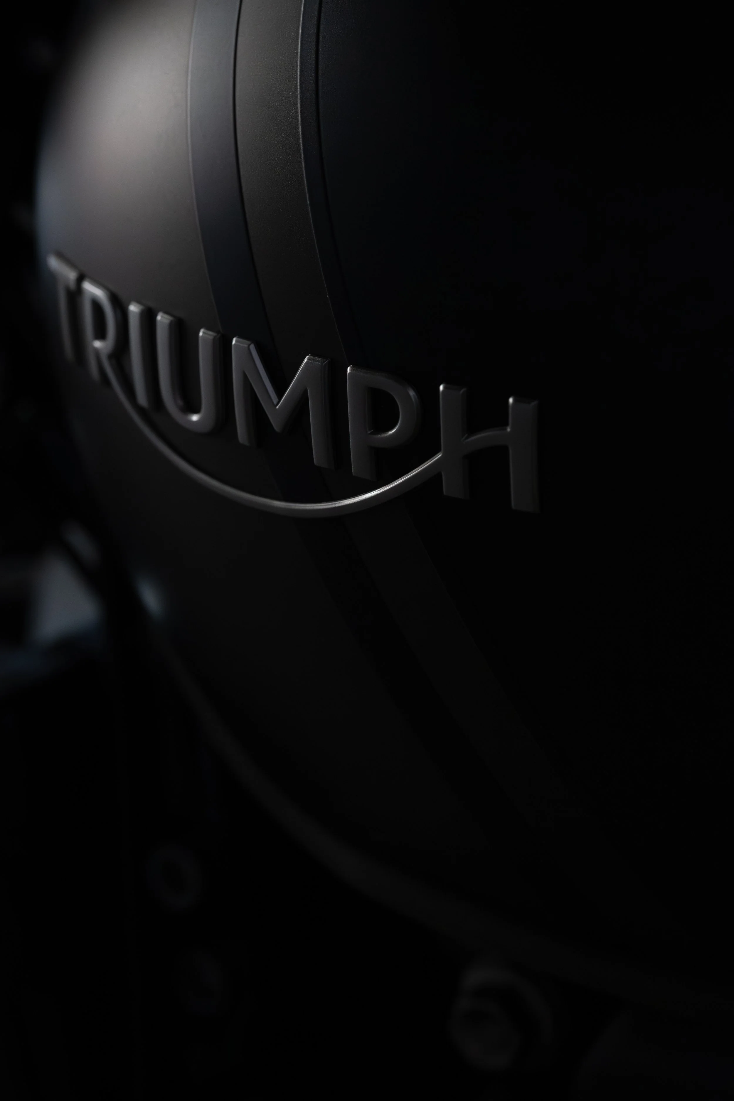 Close-up of a black Triumph motorcycle with the logo visible on the side.