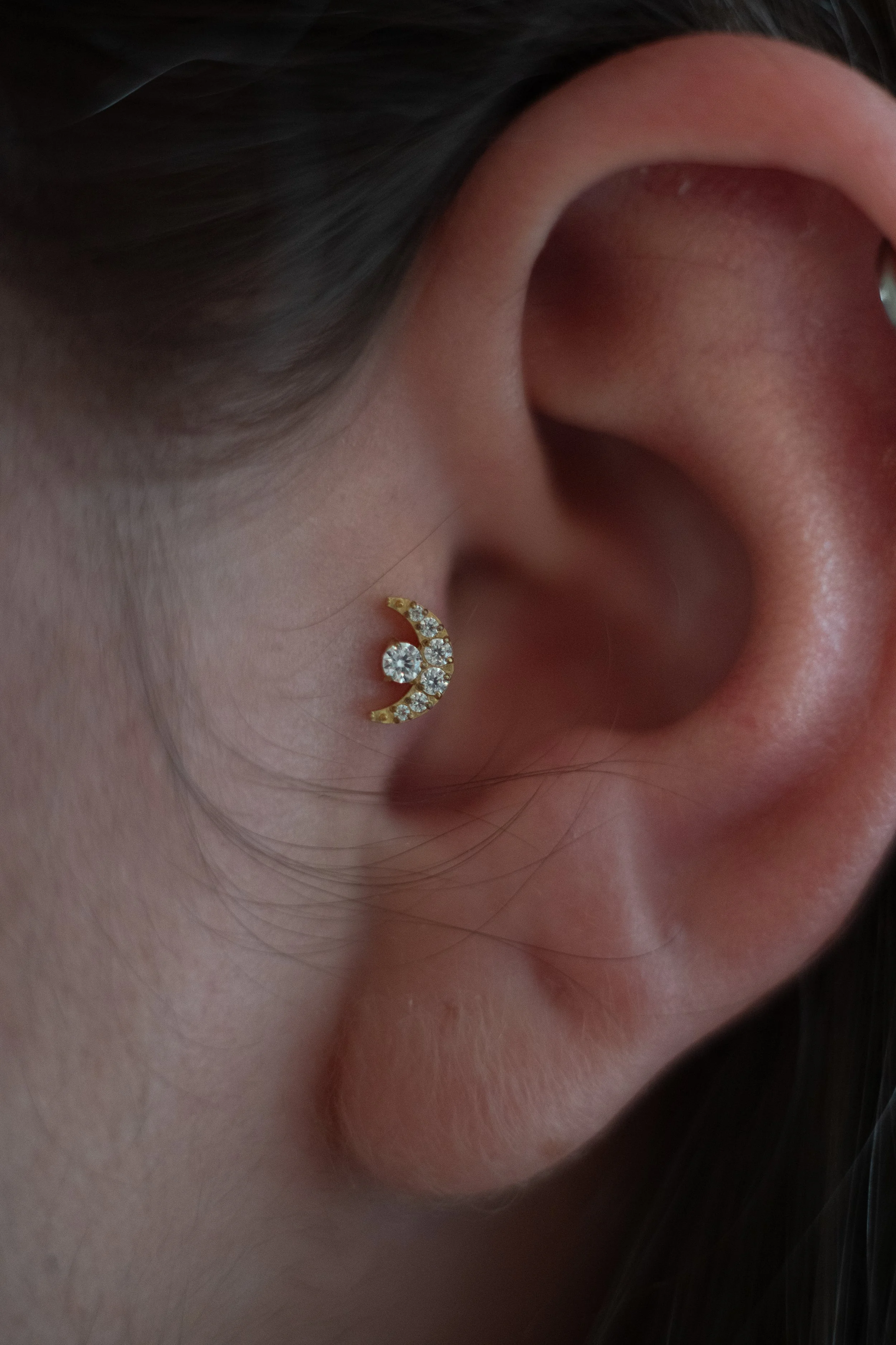 close-up d'une oreille avec un bijou en forme de croissant orné de diamants.