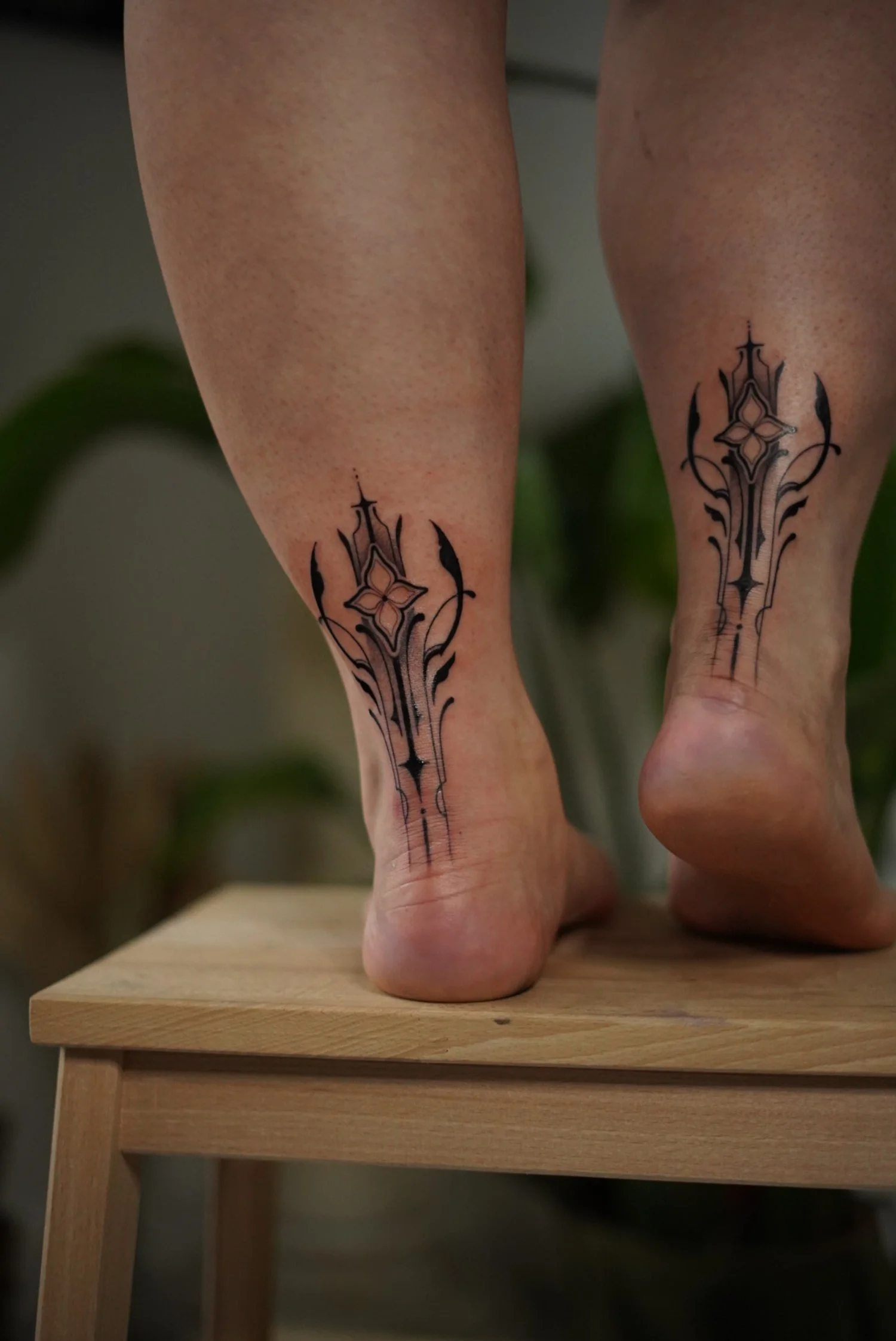 Tatouages noirs sur les chevilles de deux personnes, représentant des épées stylisées.