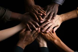 Multiple hands stacked together in a gesture of unity and teamwork.