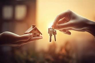 A person handing over keys to another person, with a small house model in the background, symbolizing real estate or home ownership.
