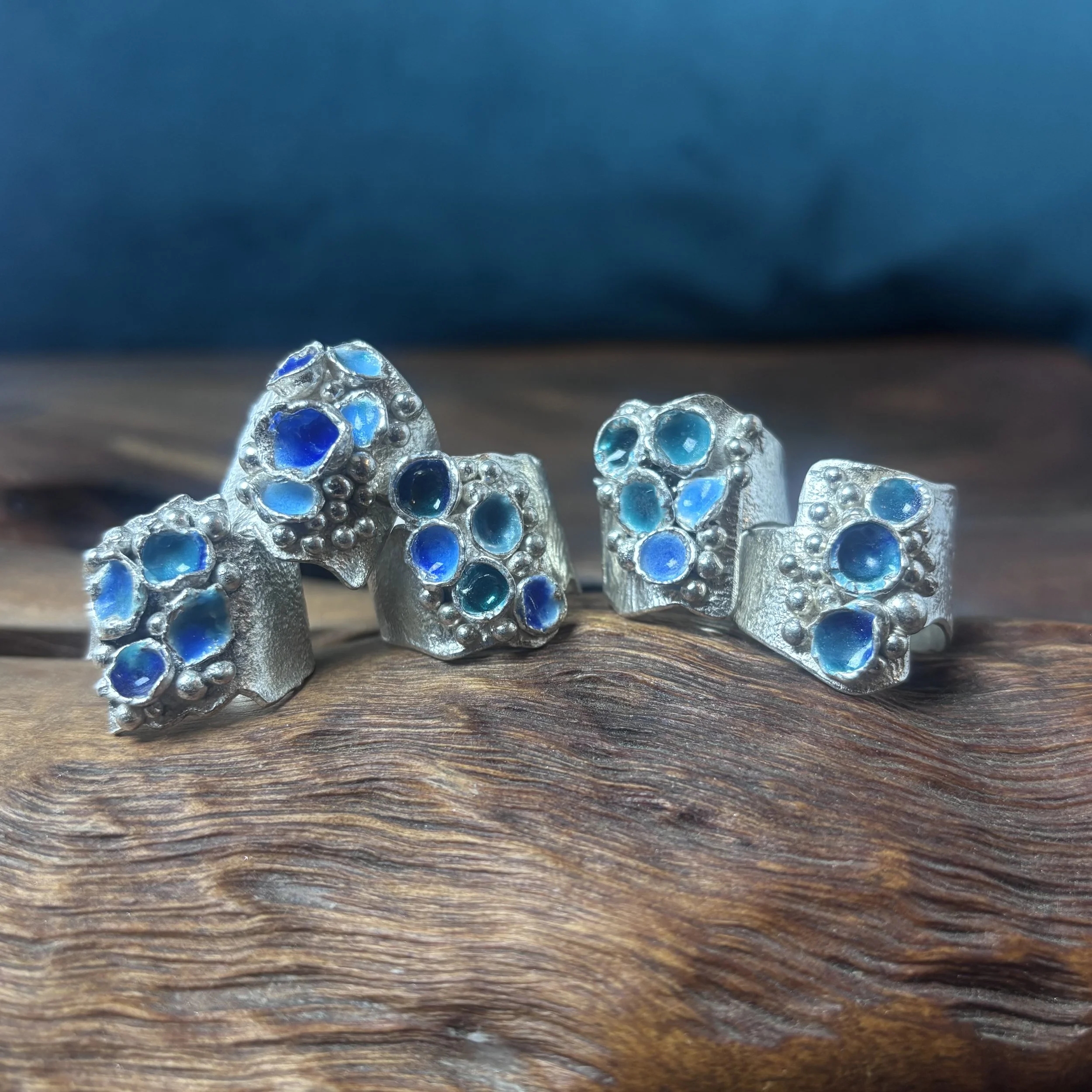 Close-up of silver jewelry pieces with blue gemstones arranged on a wooden surface.