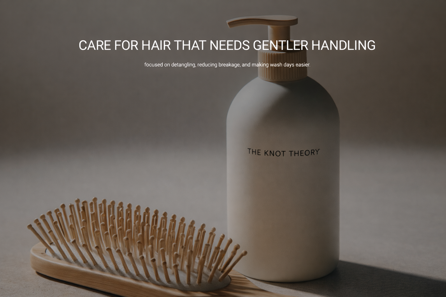 A shampoo bottle labeled 'The Knot Theory' and a wooden hairbrush with widely spaced bristles on a neutral background.