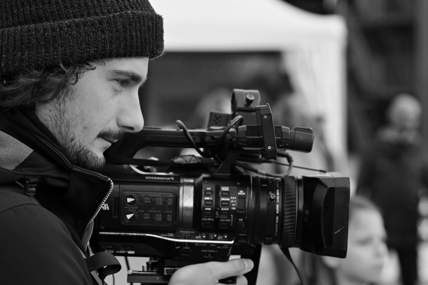 Un homme avec un bonnet noir utilisant une caméra professionnelle pour filmer.