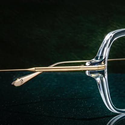 Close-up of a pair of glasses with a metallic temple and clear frame, reflecting light.