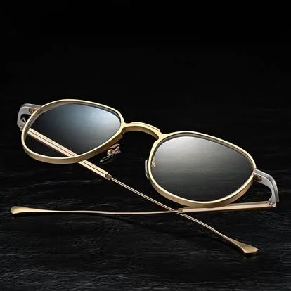 Pair of gold sunglasses with dark lenses on a black background.
