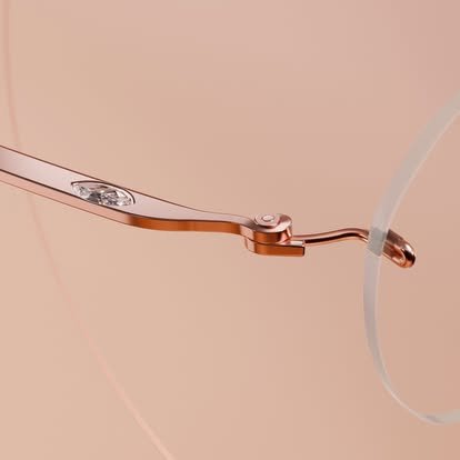 Close-up of a copper-colored eyeglass arm attached to a transparent lens.