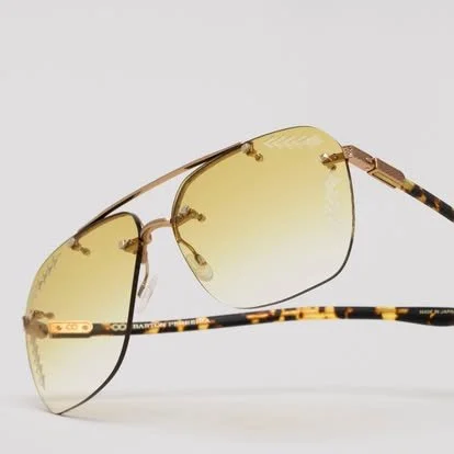 A pair of yellow-tinted aviator sunglasses with gold frames and tortoiseshell patterned temples.