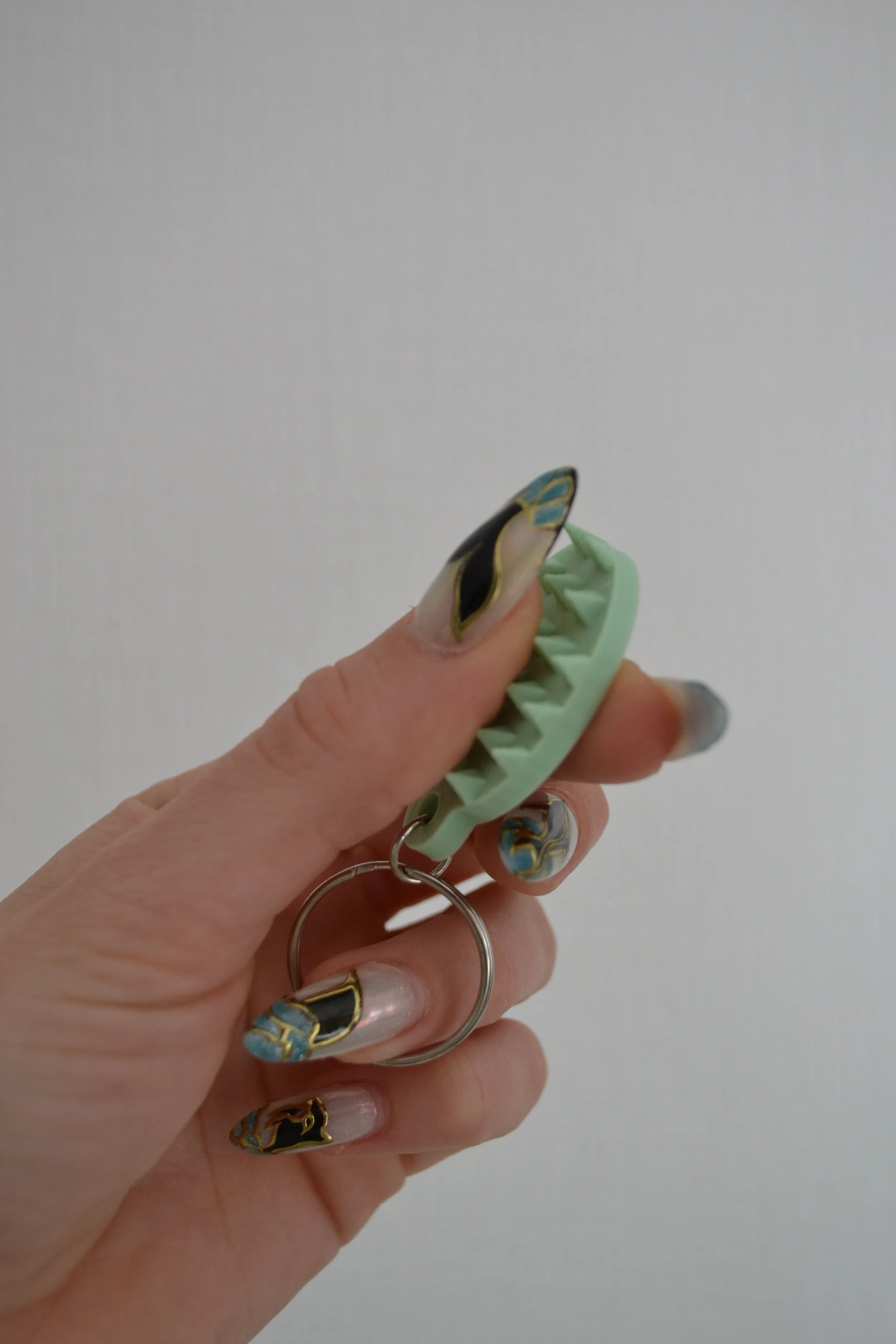 Hand holding a nail art file with decorated nails featuring marble design and gold accents.