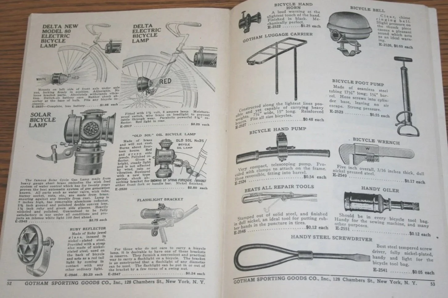Page from a vintage catalog showing various bicycle accessories including electric bicycle lamps, a solar bicycle lamp, a bicycle hand horn, a bicycle bell, a bicycle foot pump, a wrench, a flashlight bracket, a repair tool, a oiler, and a screwdrive