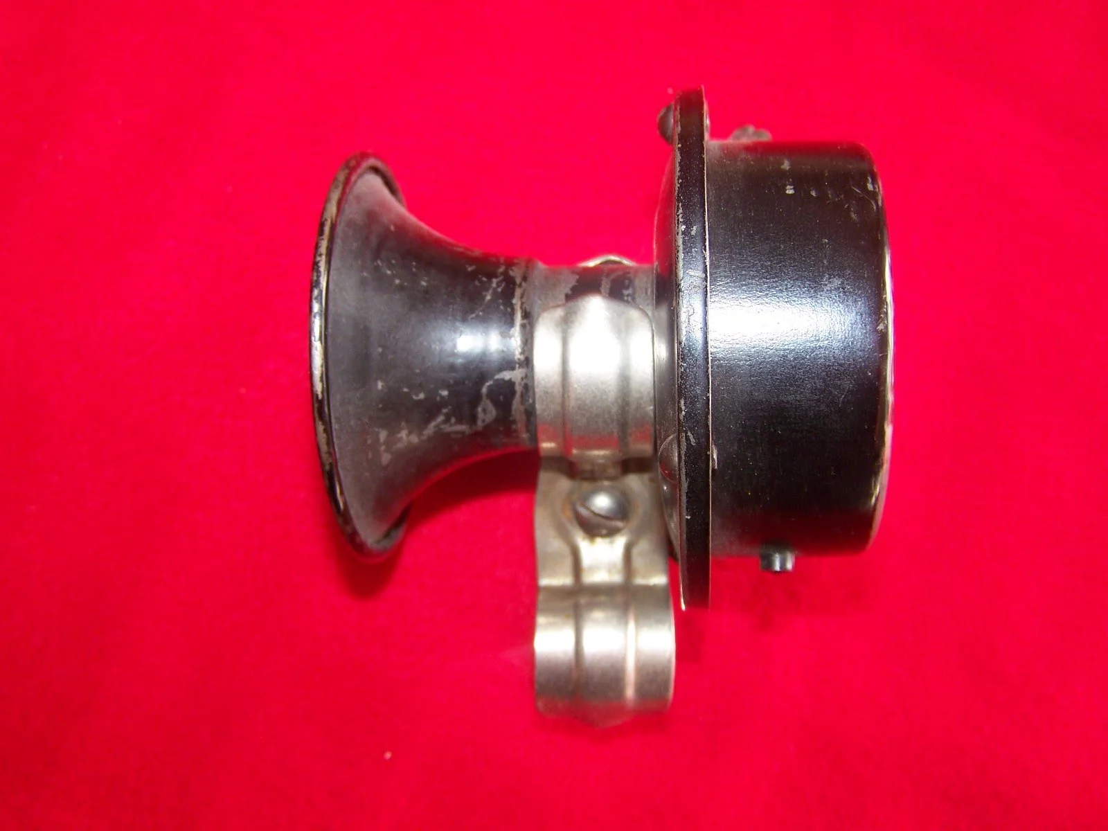 Metal mechanical part with black and silver components on a red background.