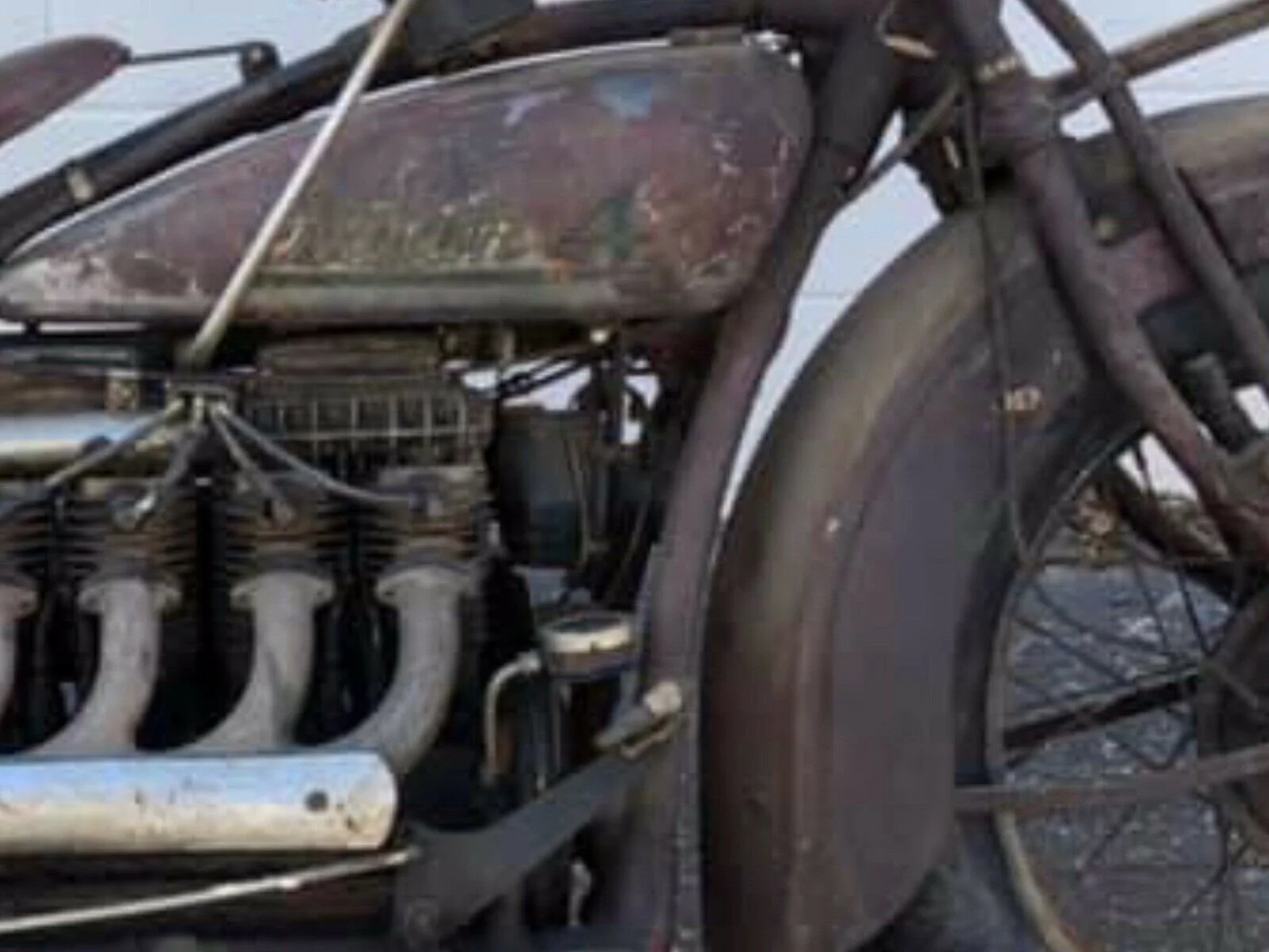 Close-up of an old, rusty, and damaged agricultural or industrial machinery with a wheel, pipes, and various mechanical parts.