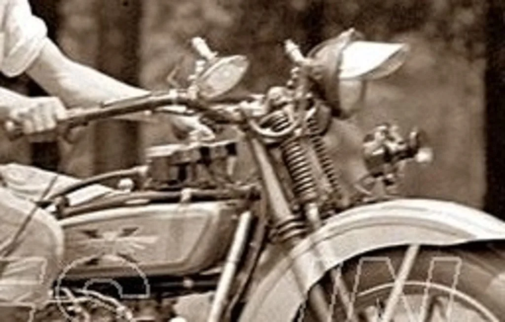 Close-up of a vintage motorcycle with a focus on the front wheel, headlight, and engine.