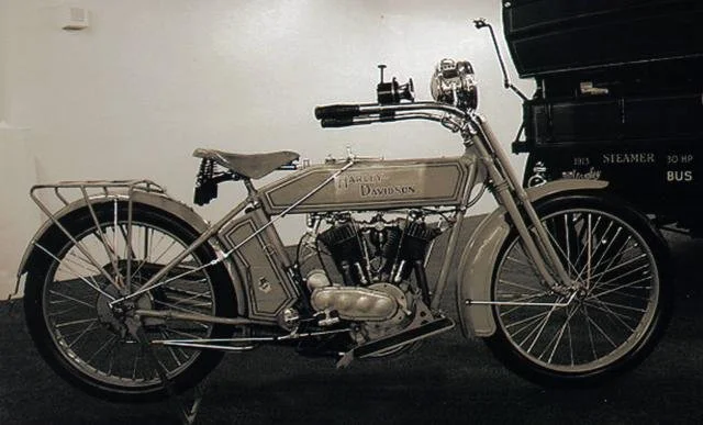 Vintage Harley-Davidson motorcycle displayed indoors with a sidecar to the right.