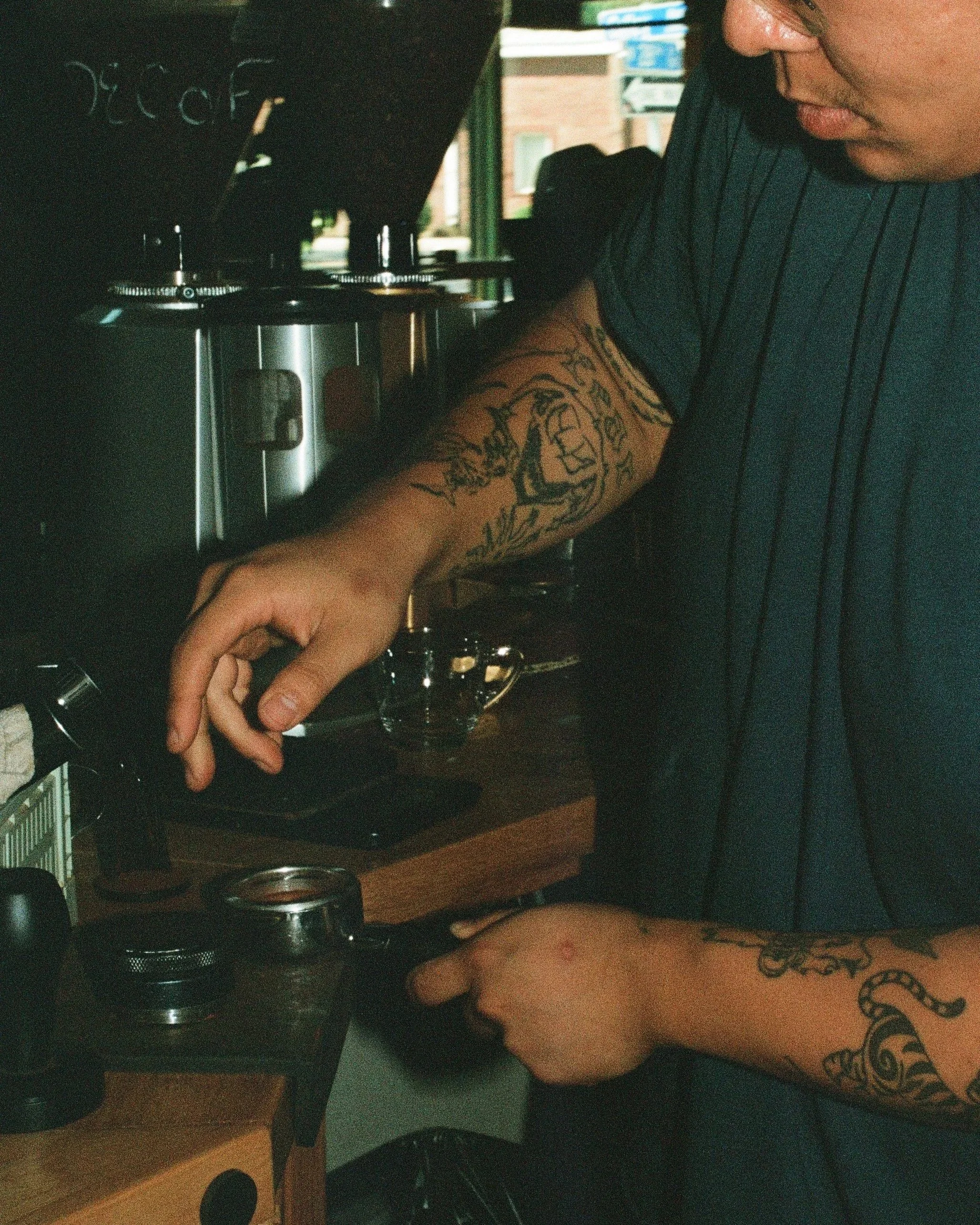 A person operating a coffee grinder or espresso machine in a coffee shop.