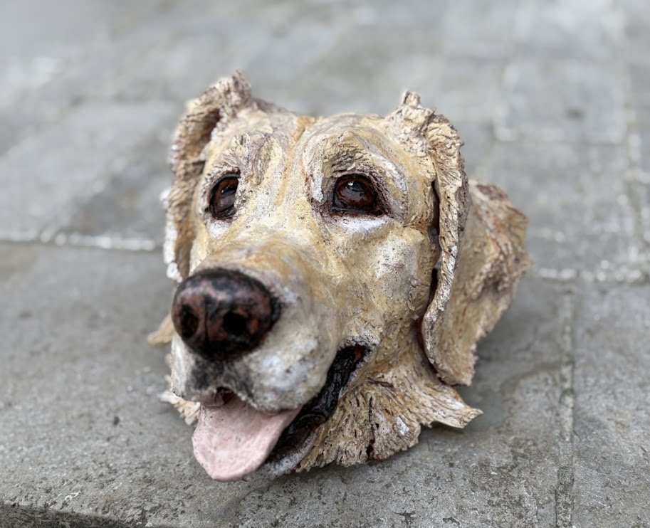 A realistic dog sculpture or mask on a gray tiled surface.