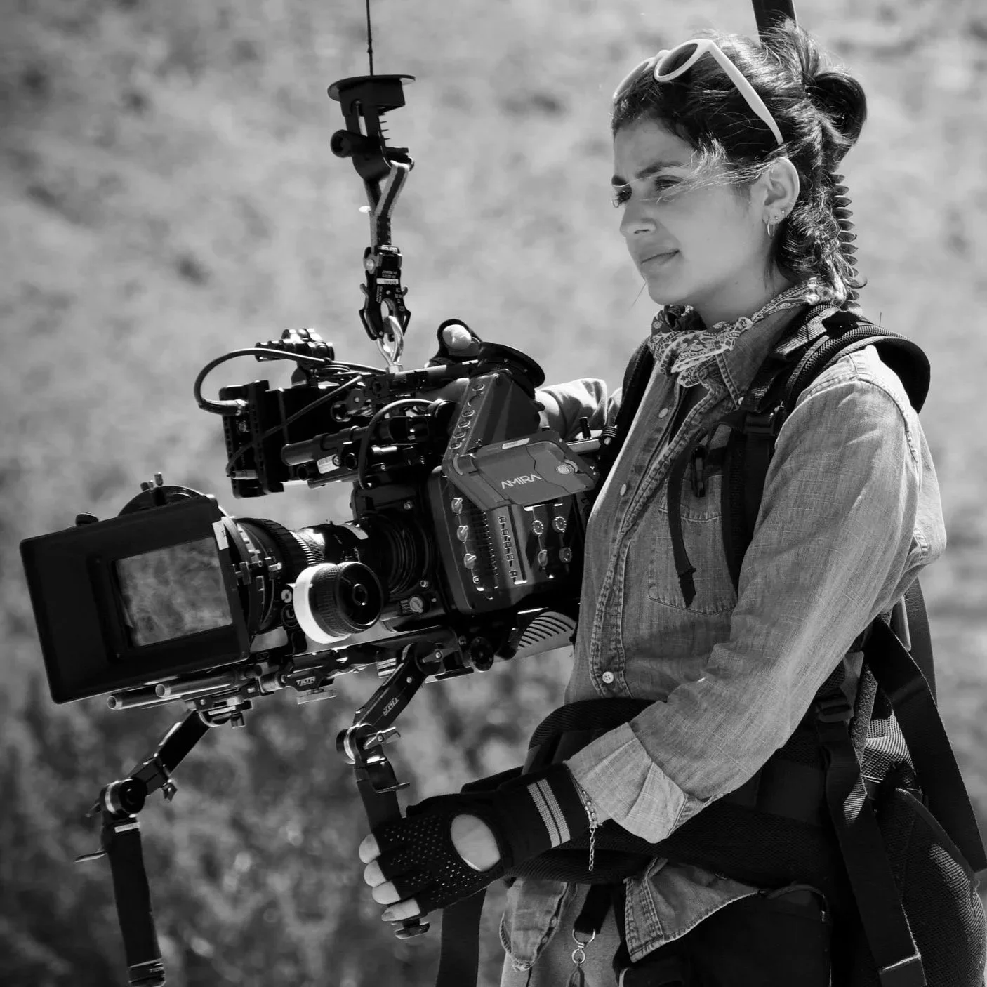 A woman with sunglasses on her head holding a professional camera mounted on a stabilizer rig.