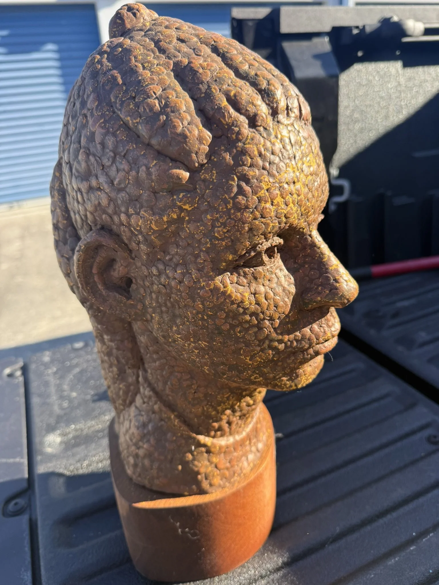 Antique bust sculpture made from a rough, textured material with a rust-like appearance