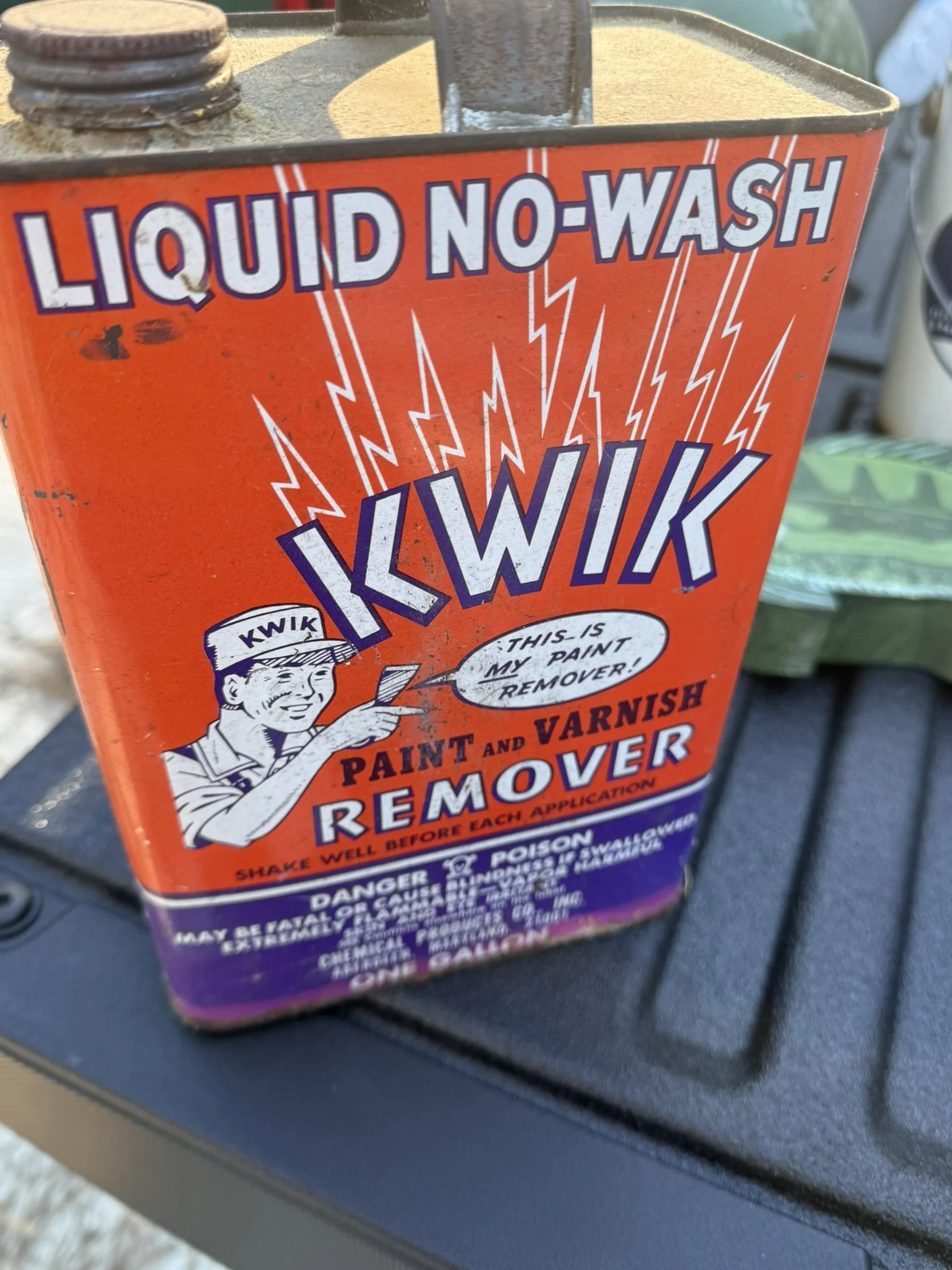 A bright orange container labeled 'Liquid No-Wash Ikwik Paint and Varnish Remover' with a picture of a man holding a paintbrush and speech bubble saying 'This is my paint remover!'