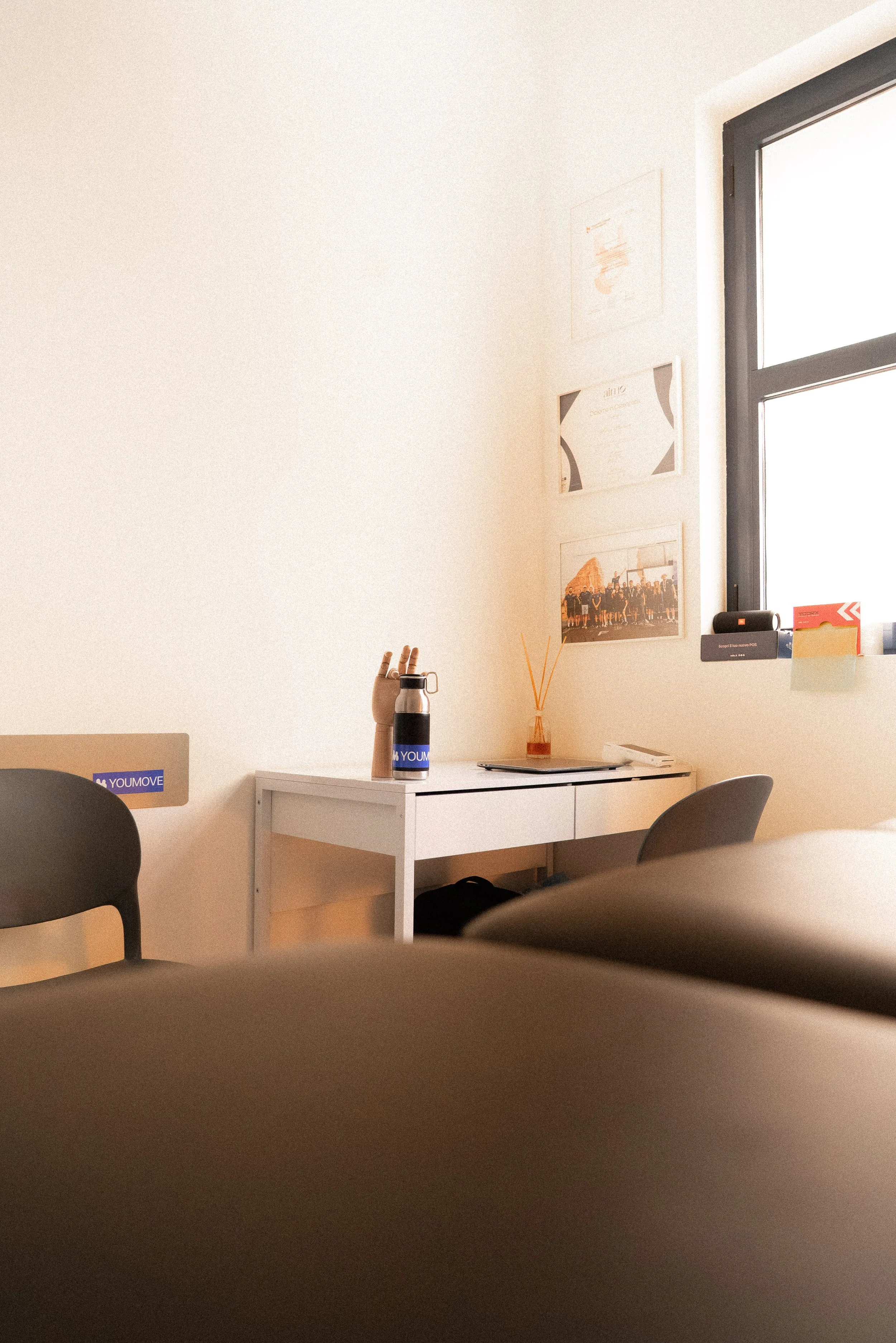 Camera rivolta verso una scrivania bianca vicino a una finestra con pareti bianche e decorazioni sulla parete.