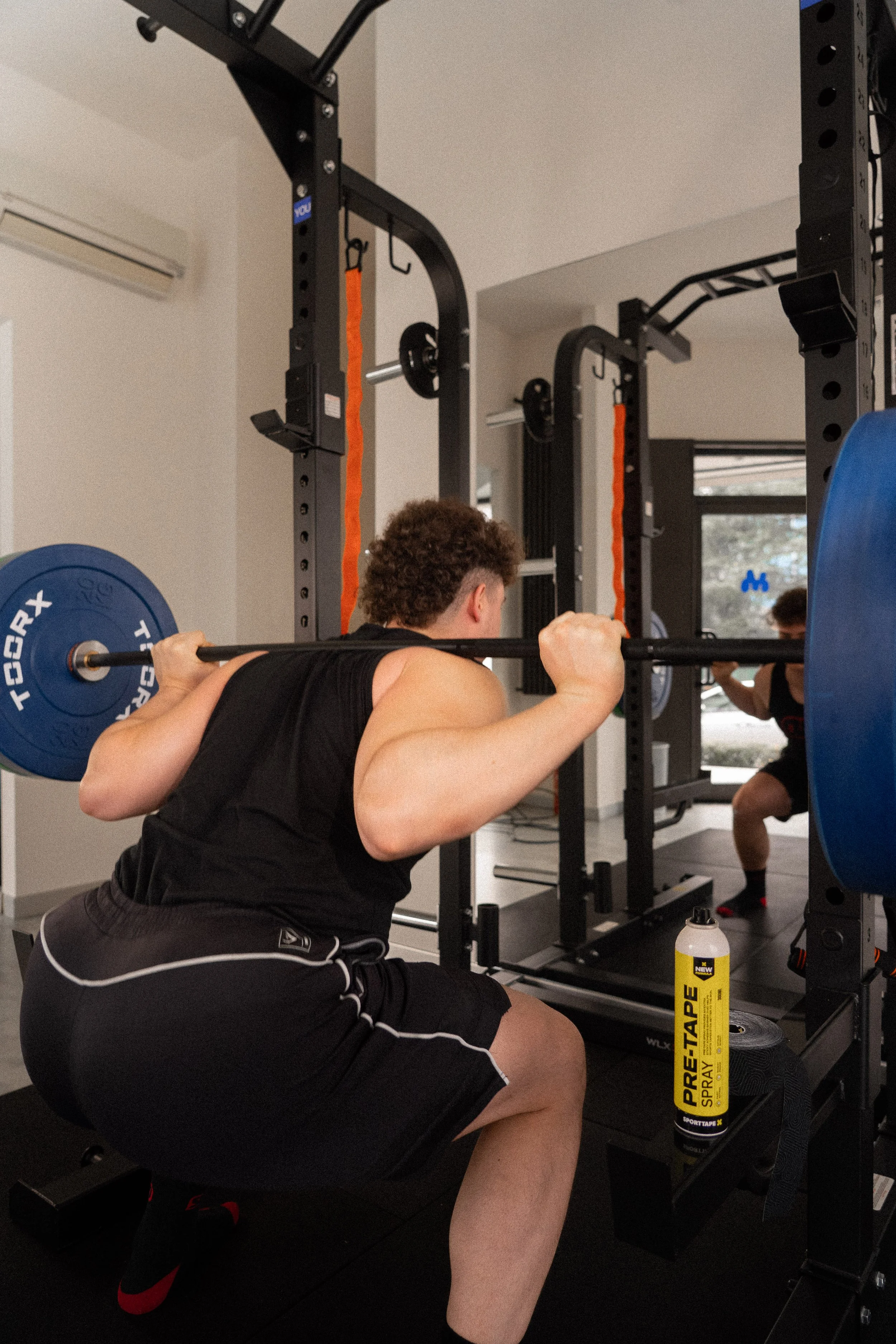 Un uomo sta facendo squat con un bilanciere nella palestra.