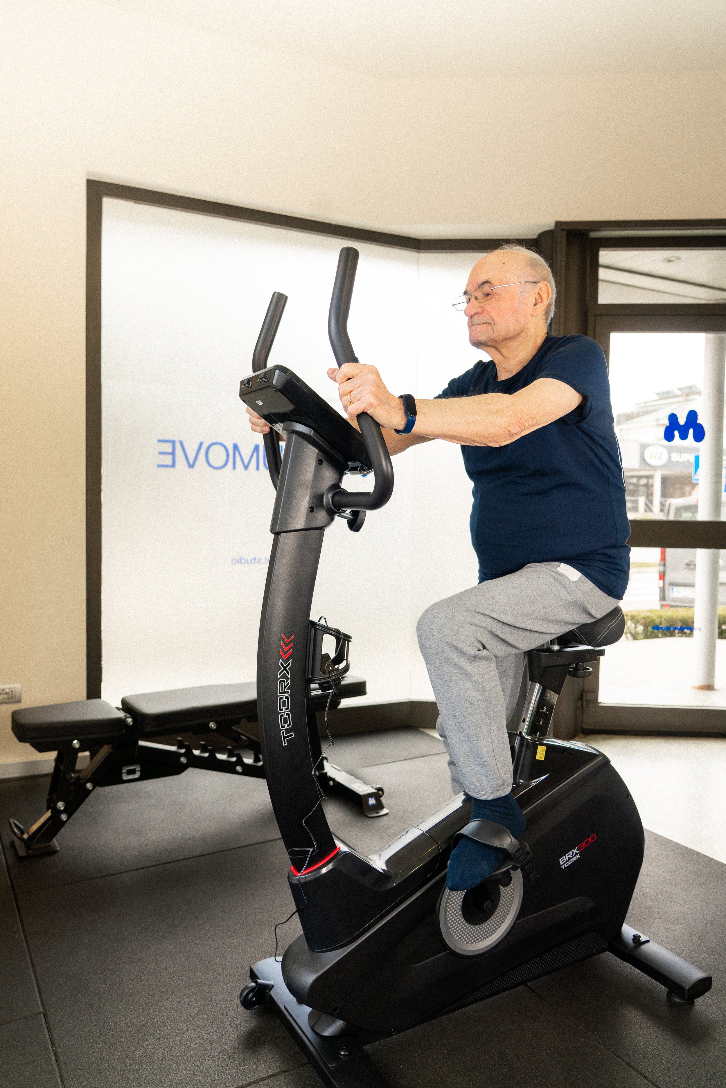 Anziano che fa esercizio su una cyclette in palestra.