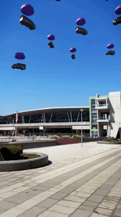 Carros suspendidos en paracaídas flotando en el cielo con fondo de edificio moderno.